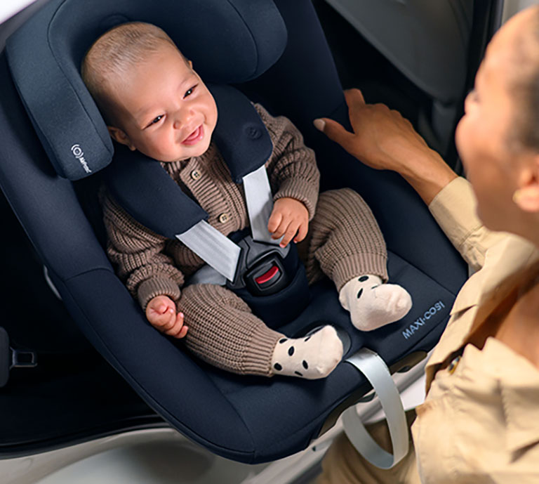 Image showing a baby in a Maxi-Cosi Mica 360 Pro car seat with their mother rotating and sliding them out of the car.
