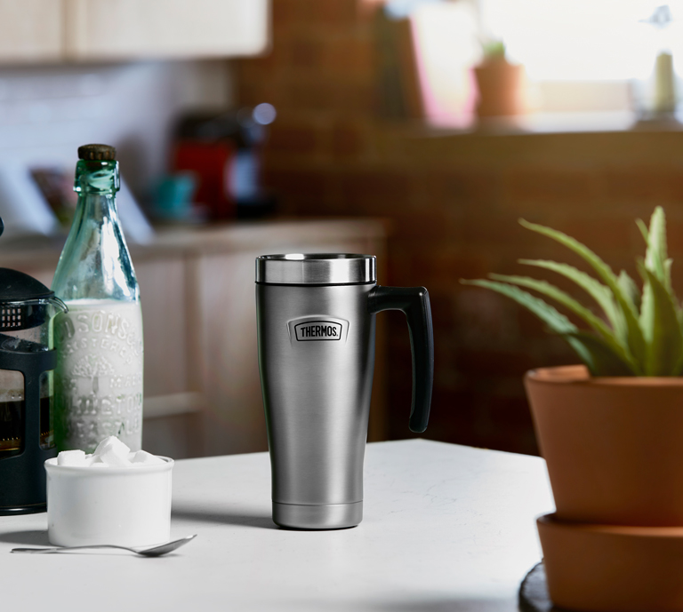 Thermos travel Mug on kitchen table with plant and coffee