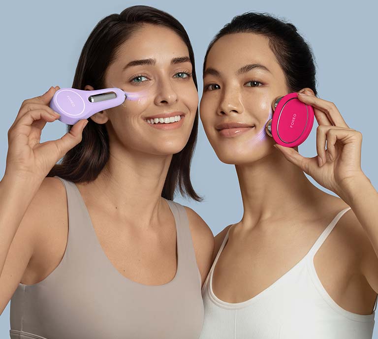 2 women holding Foreo microcurrent devices to their face to demonstrate usage, whilst smiling